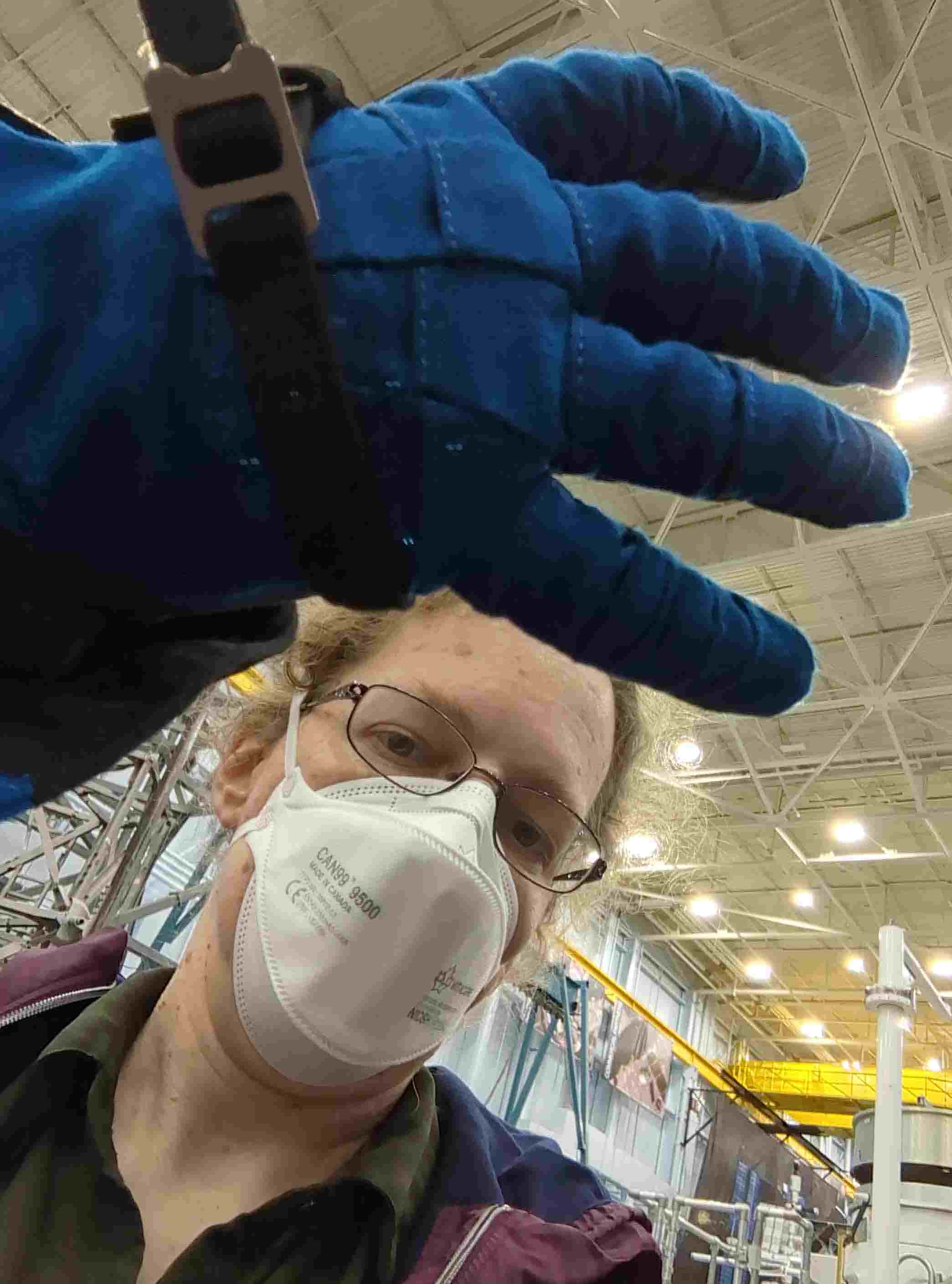 a reporter with her gloved spacesuit hand in front of the camera