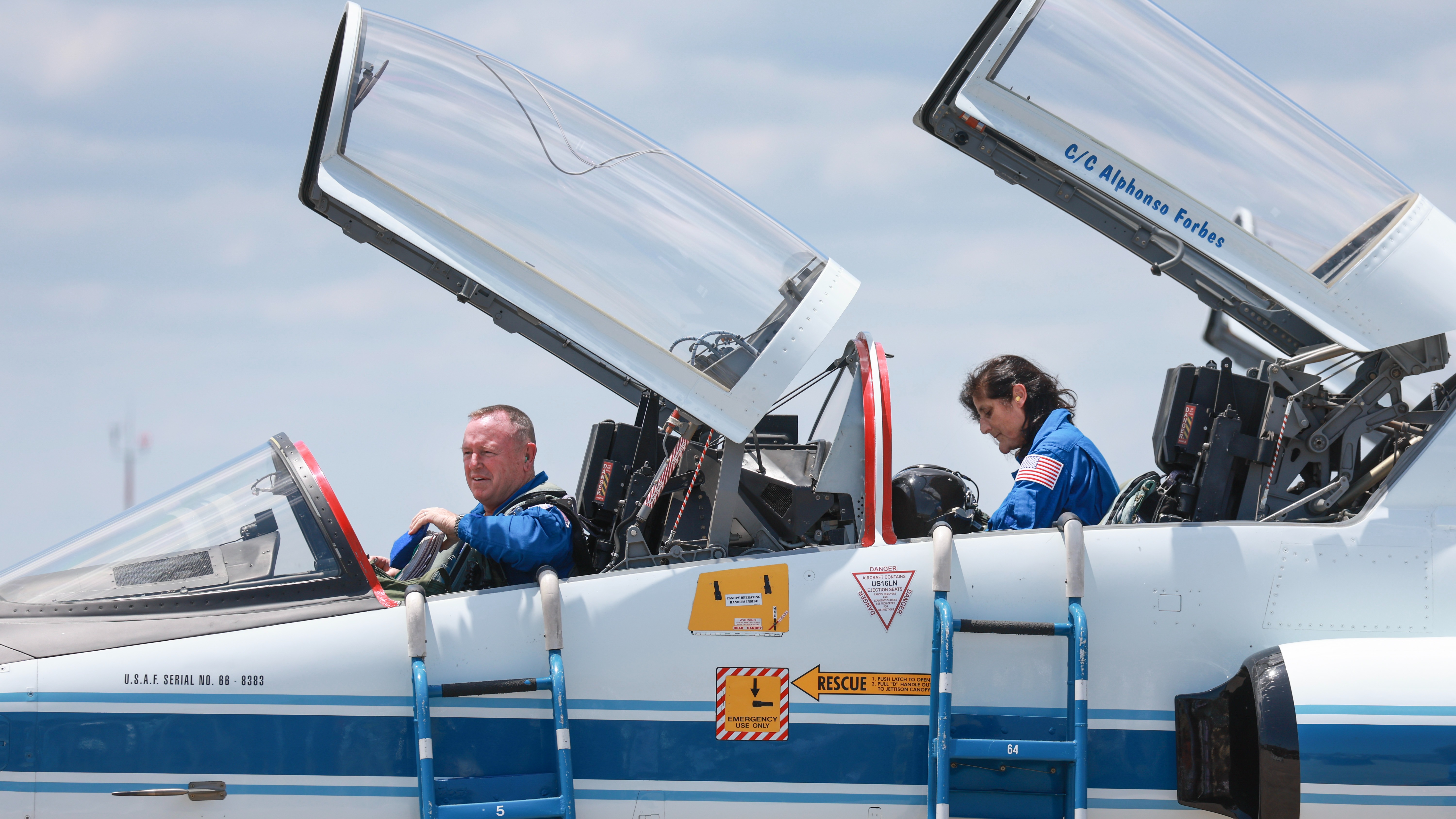 two astronauts inside a jet with cockpit windows open