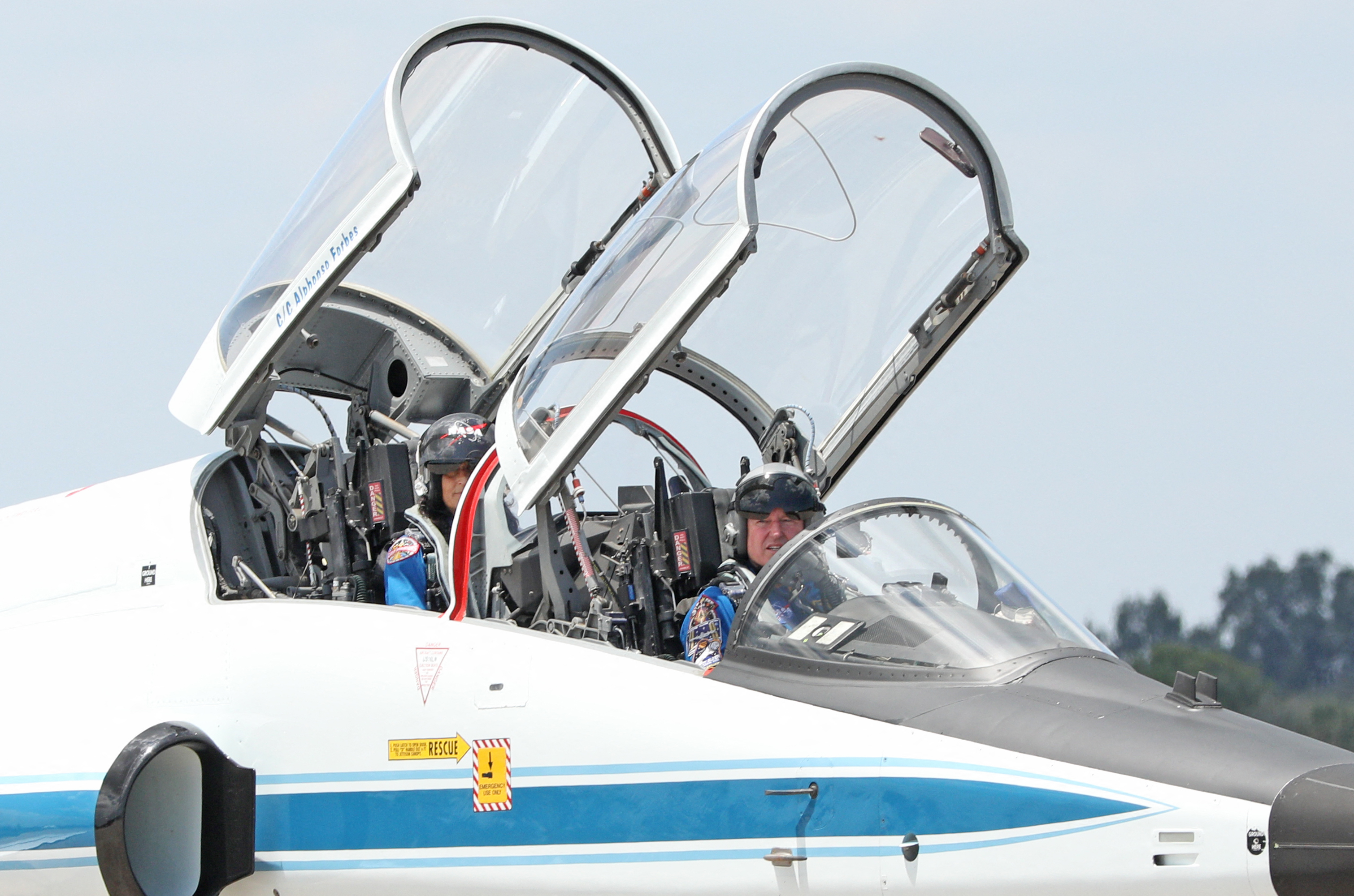 two astronauts in helmets inside a jet with cockpit windows open