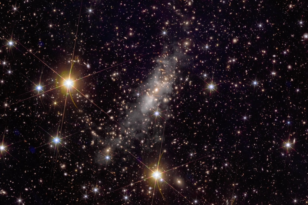 This image is a higher resolution, close-up cutout from a wider frame featuring galaxy cluster Abell 2390. It shows the ‘intracluster light’ – light emitted by stars that have been torn away from their parent galaxies – in enhanced white-grey colouring. This hints at the distribution of dark matter in both the cluster and associated filament of the ‘cosmic web’. Image credit: ESA/Euclid/Euclid Consortium/NASA, image processing by J.-C. Cuillandre (CEA Paris-Saclay), G. Anselmi; CC BY-SA 3.0 IGO or ESA Standard Licence.