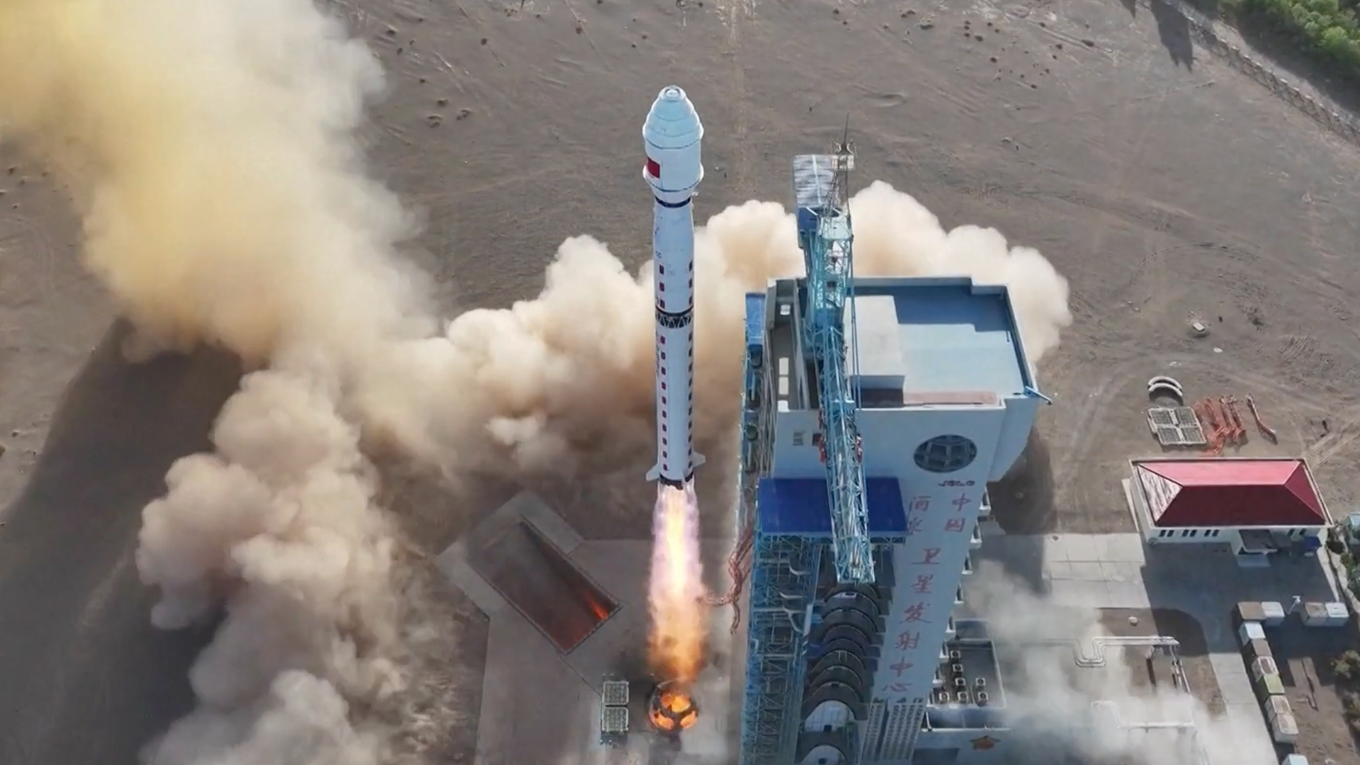 a white rocket lifts off in the desert above a cloud of dust and smoke