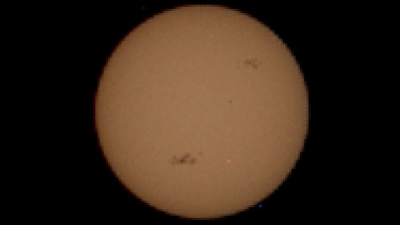 a grainy image of the sun showing two black spots on its visible disk