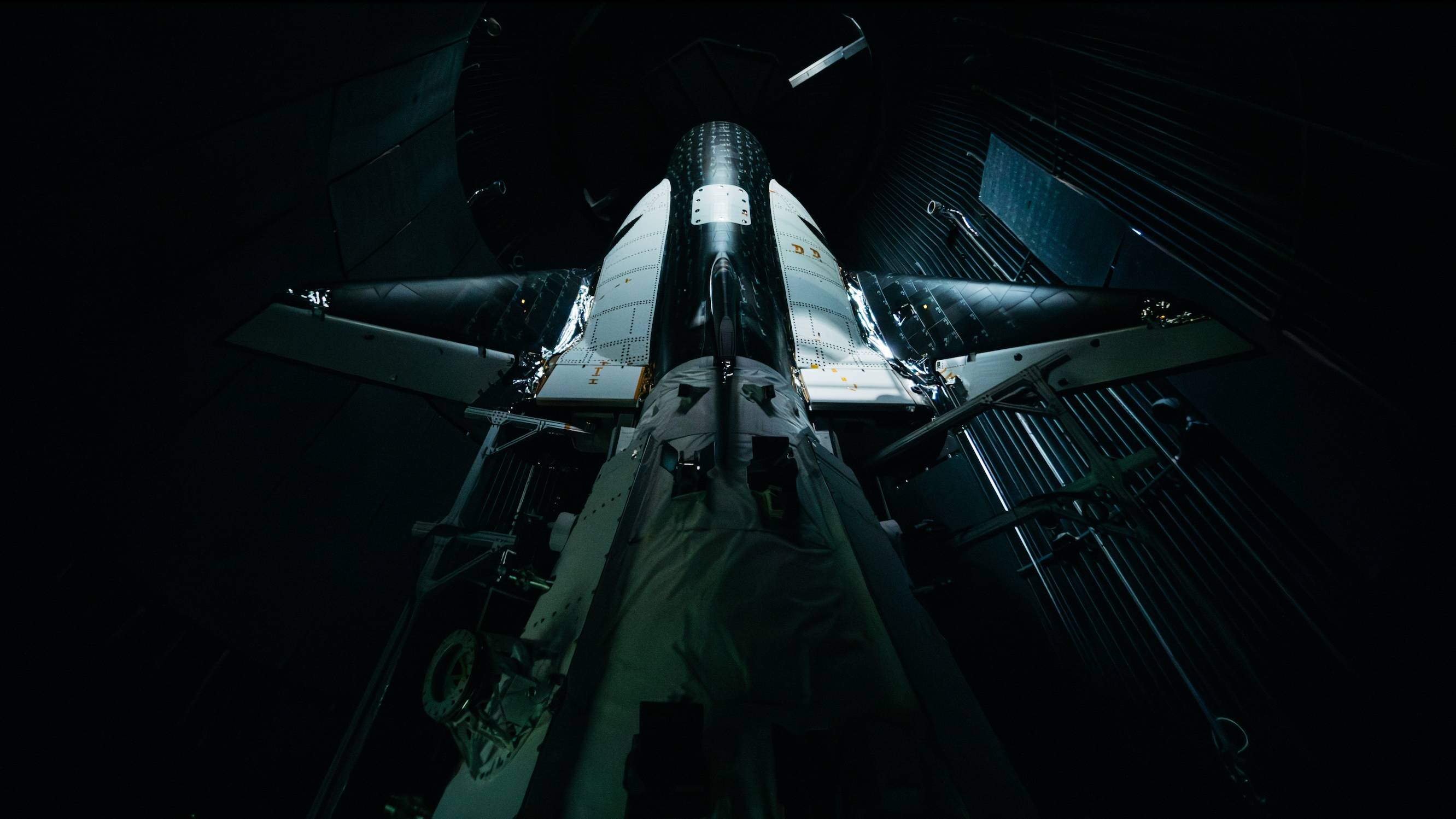 a white and black space plane sits in a dark room